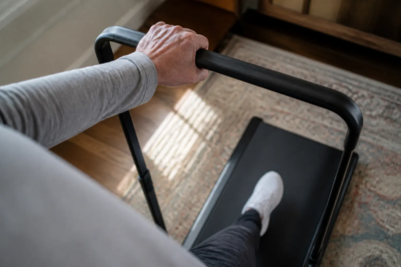Older adult holding a walking pad handle while stepping on