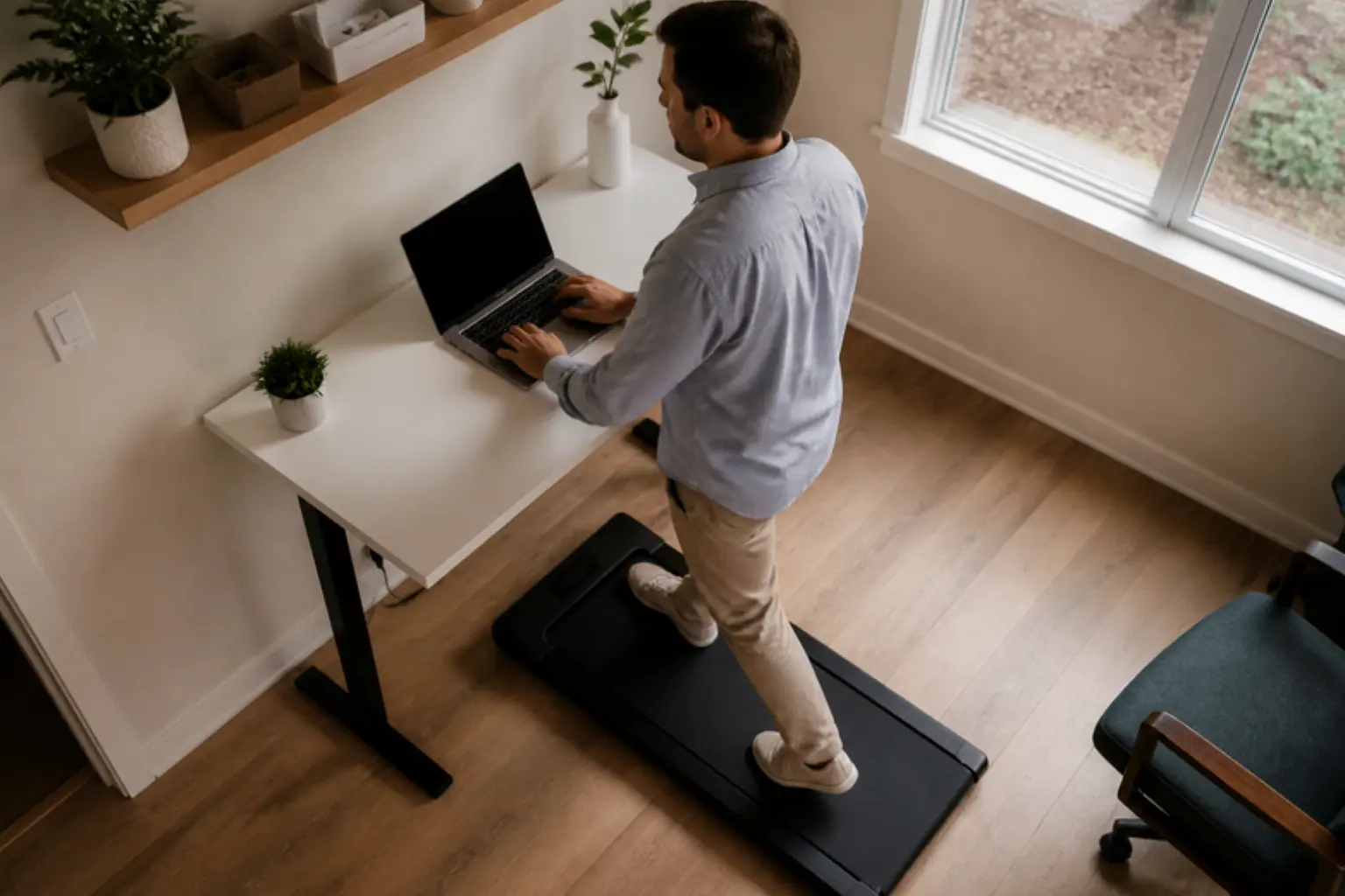 Man walking on a flat walking pad under a standing desk